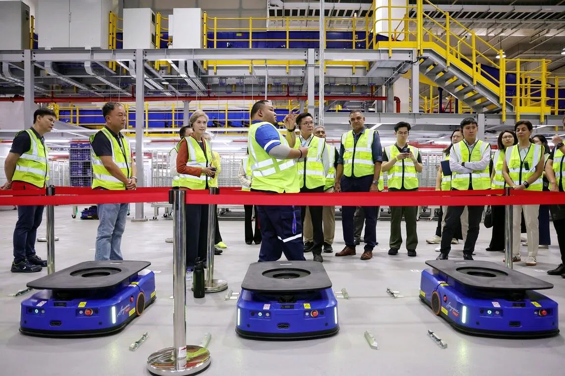 Minister for Digital Development and Information Josephine Teo (third from left) touring SingPost’s automated parcel sorting facility at its Regional eCommerce Logistics Hub in Tampines on June 9.