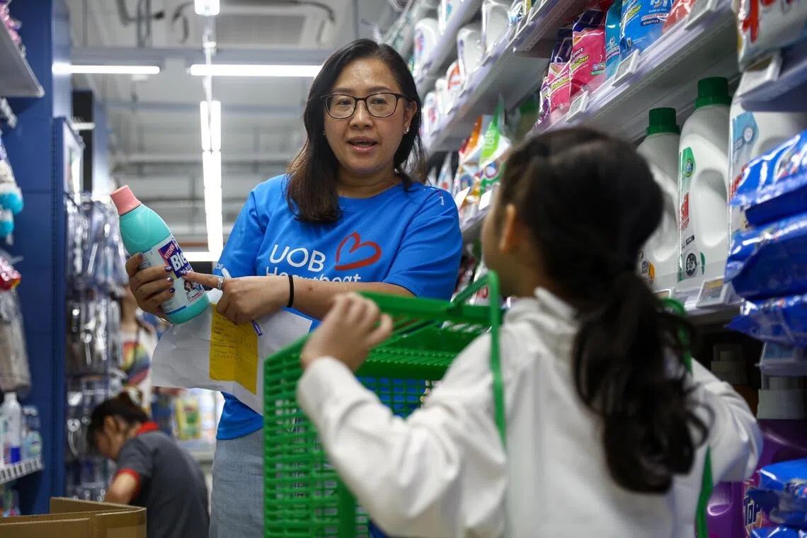 UOB Heartbeat volunteer Jane Lai (left) pointing out the bleach on Jariss’ shopping list.