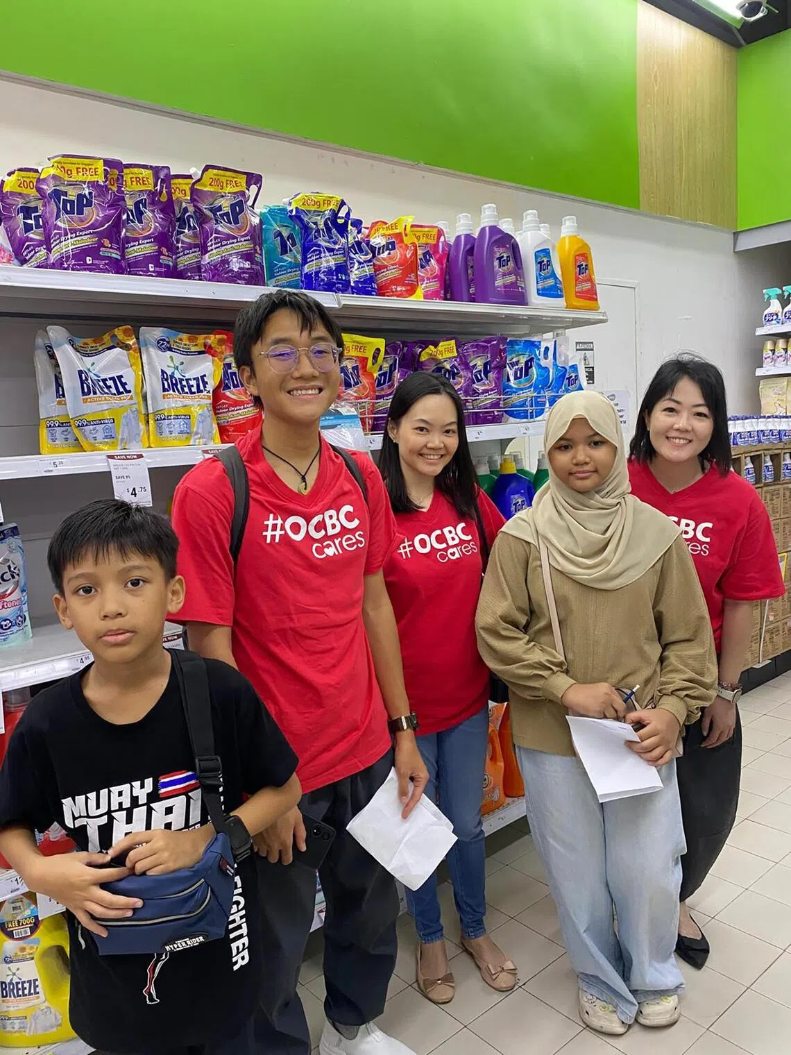 OCBC volunteers with siblings Ryyan Aaryz, nine, (in black) and Mikhayla Milan, 11, (in brown) during a grocery run, where the children were taught the importance of budgeting and making informed nutrition-focused decisions.