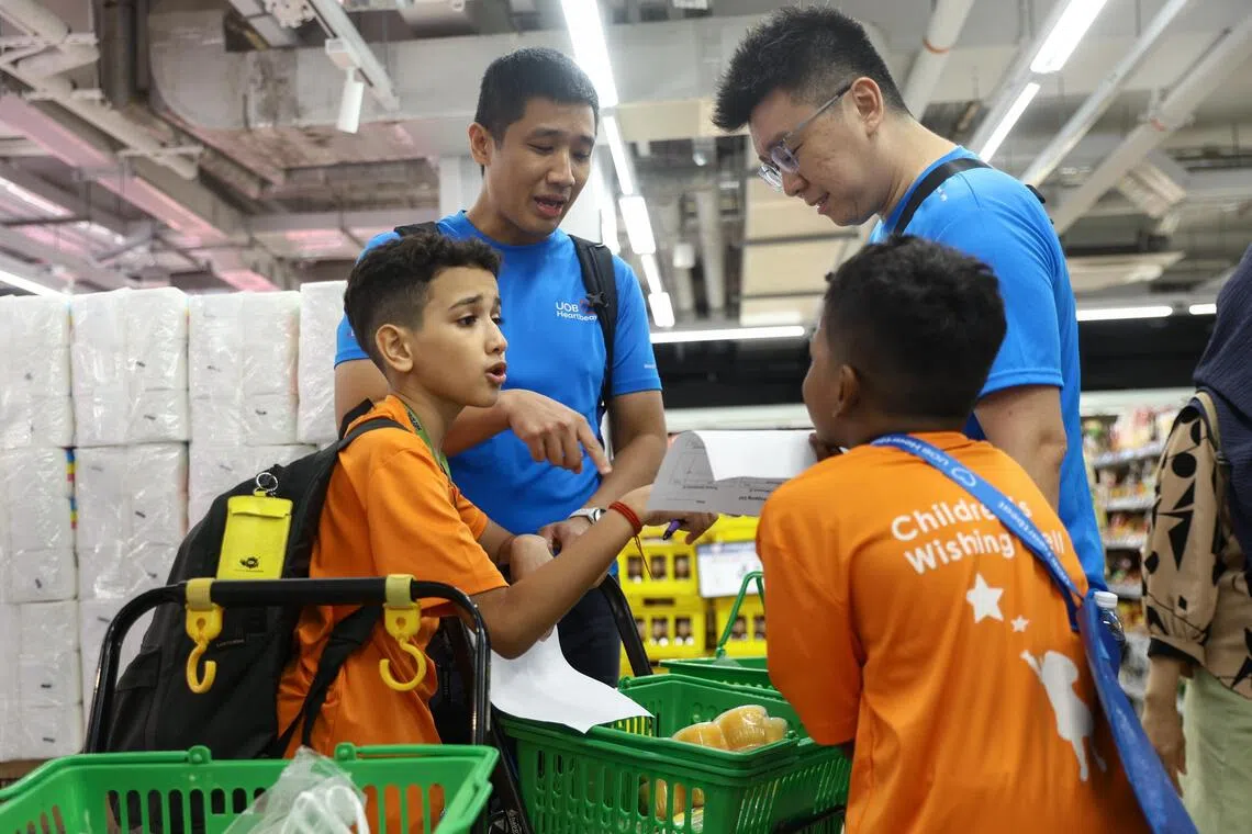 (From left) Aaron Kishen Arun Pandian Pillai, 11; UOB Heartbeat volunteers Lim Gene Harn and Derrick Sin; and Aaron’s brother Leon Shrishen Arun Pandian Pillai, nine, discussing how to deconflict their shopping lists.