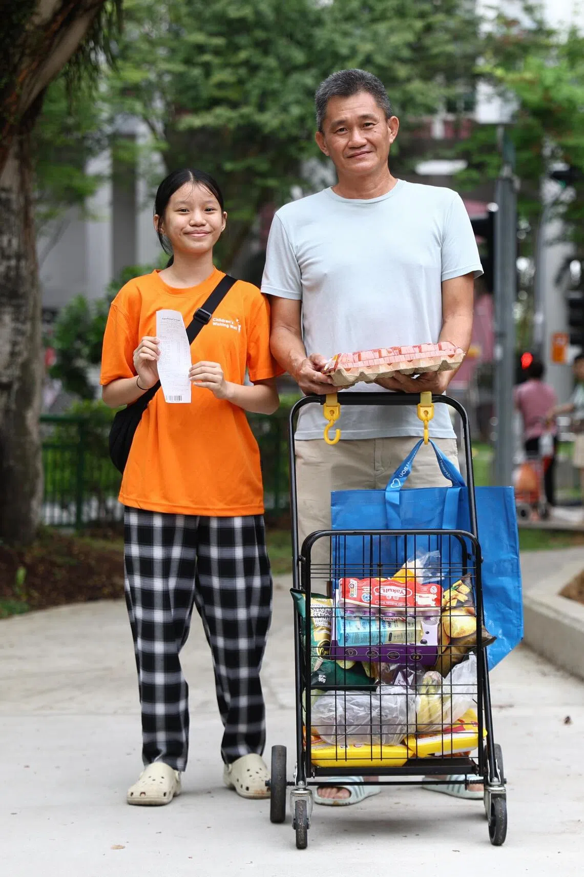 Najwa Chua Ai Xin (left), 12, and her father, Chua Peng Huat, 54, with her grocery purchases and receipt.